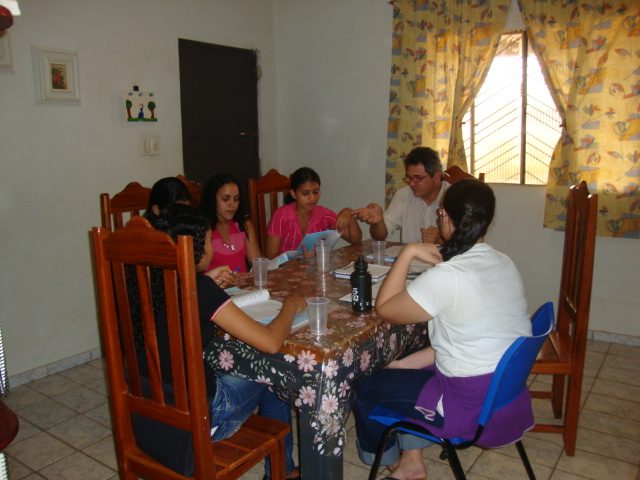 Família reunida em volta da mesa lendo o material do programa