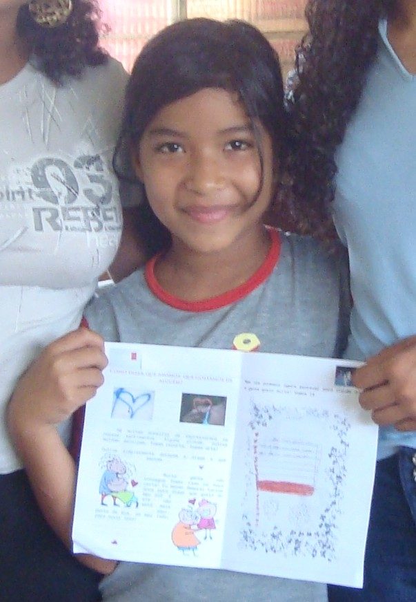 Menina sorrindo e mostrando a folha do material do programa
