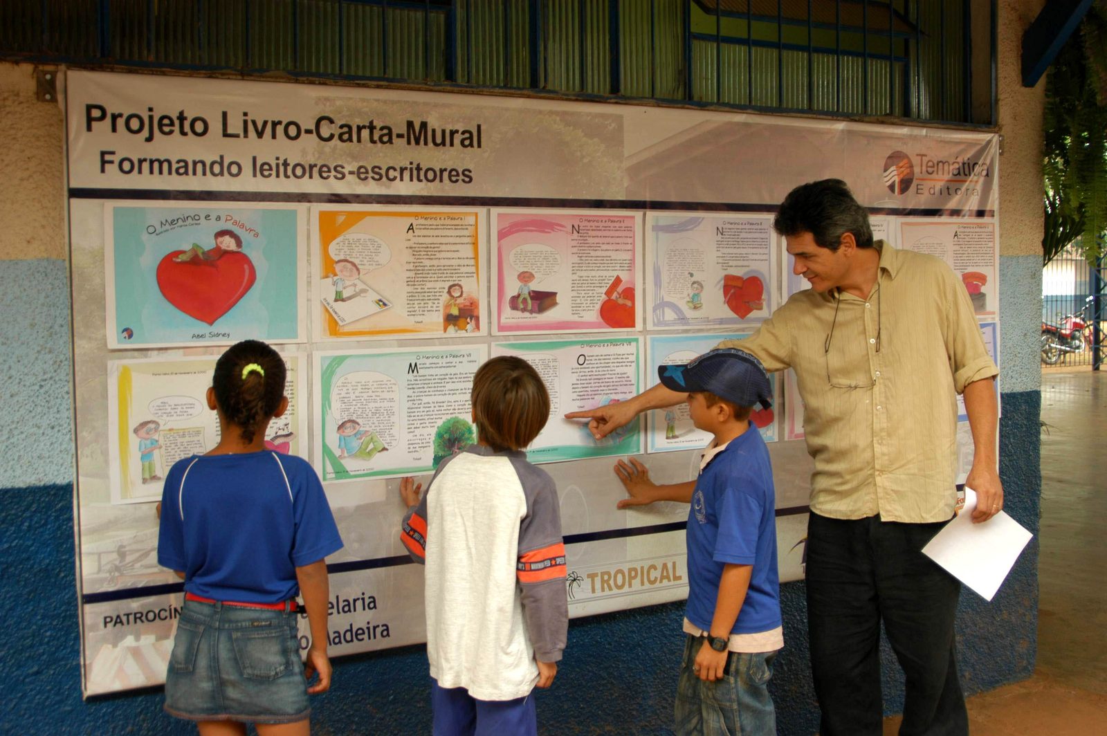 Crianças diante do mural do Projeto Livro-Carta-Mural, com o subtítulo Formando leitores-escritores